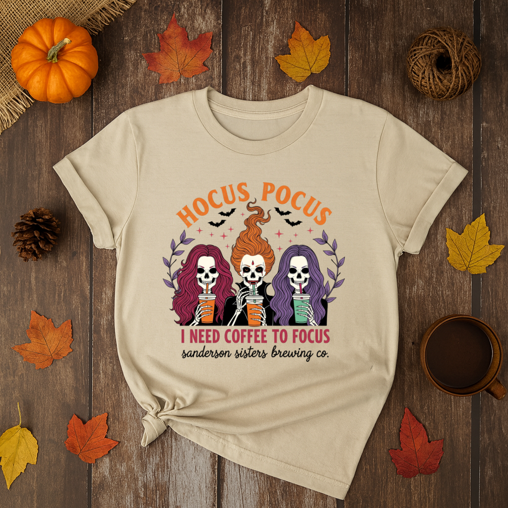 Halloween t-shirt with Sanderson Sisters skeletons holding coffee cups and text “Hocus Pocus I Need Coffee to Focus” – spooky coffee lover tee.
