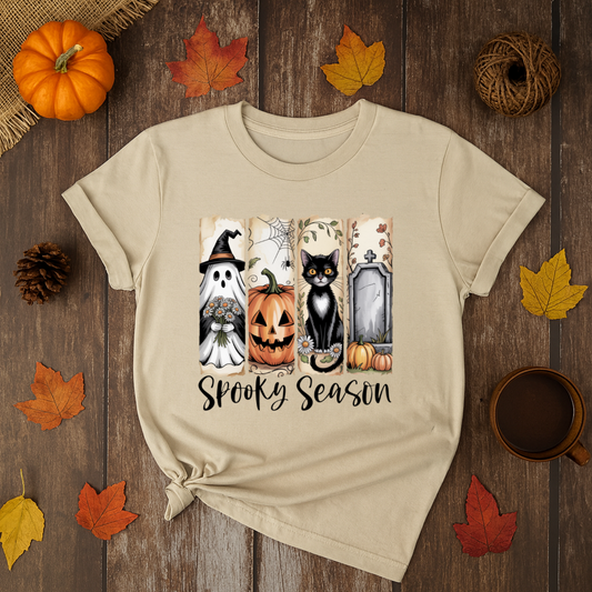 Spooky Season Halloween t-shirt with ghost, pumpkin, black cat, and gravestone graphic on beige shirt.